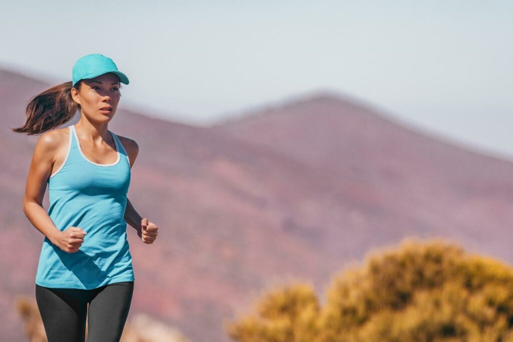 Une femme de La Réunion traversant le Cirque de Mafate à La Réunion, avec un sentier escarpé et une vue spectaculaire sur les montagnes