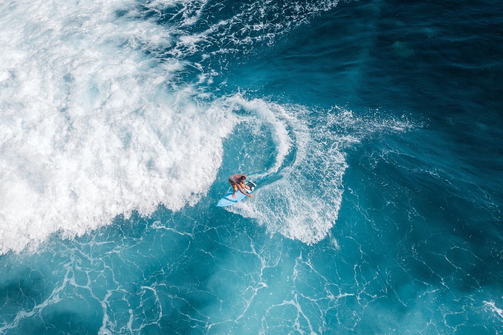 Manœuvre sur une vague à La Réunion Surfer en train de tailler un virage sur une vague bleue à La Réunion, vue aérienne