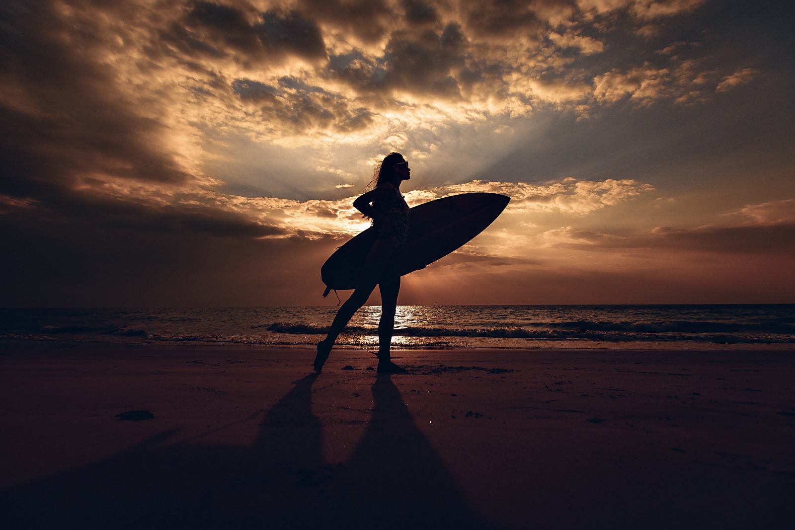 Silhouette de surfeuse à La Réunion Silhouette d’une surfeuse avec sa planche sur une plage de La Réunion au crépuscule