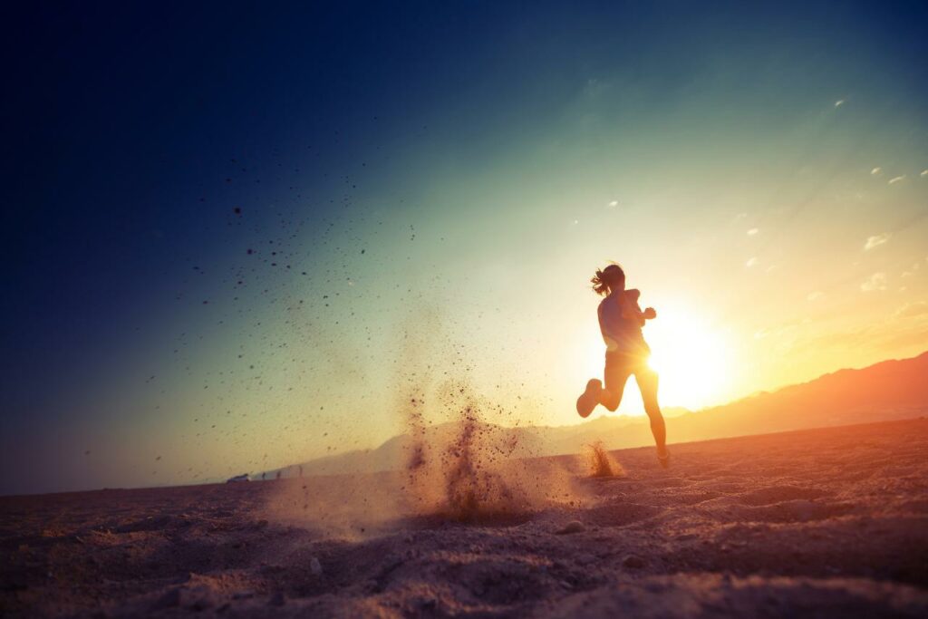 Coureur participant à un trail nocturne à La Réunion, illuminé par un coucher de soleil avec les montagnes en toile de fond