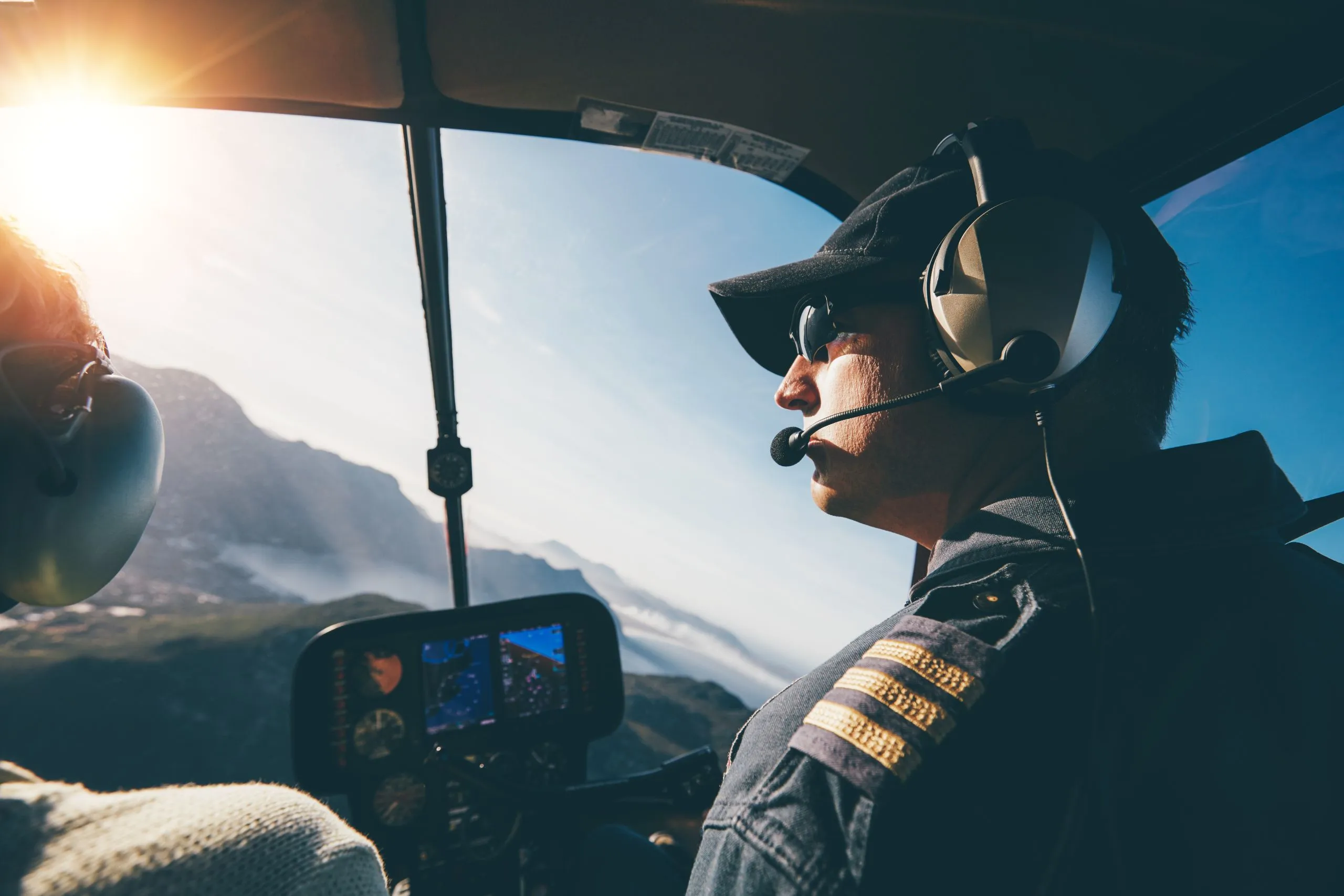 Pilote avec passagère émerveillée par la vue sur les cirques de La Réunion depuis un hélicoptère au crépuscule