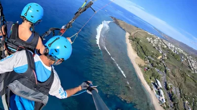 Parapente en vol au-dessus de La Réunion — vue aérienne sur le lagon et les pentes volcaniques