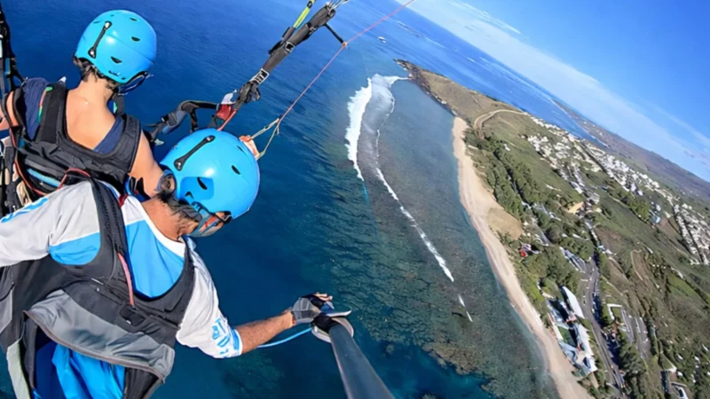 Parapente en vol au-dessus de La Réunion — vue aérienne sur le lagon et les pentes volcaniques
